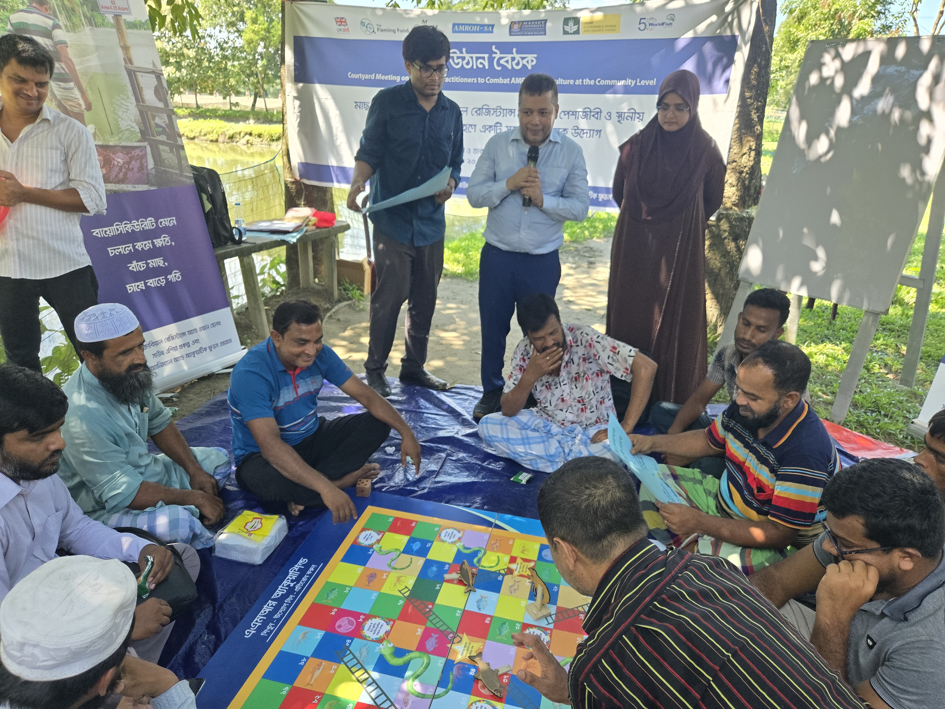 Facilitators are facilitating the AquaShield snakes and ladders learning game. Photo: K.M. Shkhawat Hossen.