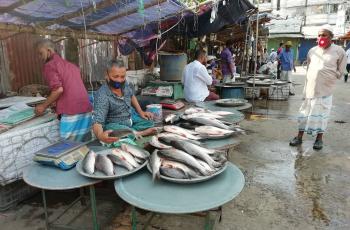 Masked retailers sell fish at a market in Chandpur, Bangladesh. Photo by Kingkar Shaha.