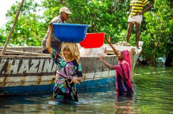 This group of photos captures the fish processing journey from the moment the fish is landed from the sea to its final distribution. The images highlight key stages, including offloading from fishing vessels, boiling to preserve quality, sun-drying for longer storage, and packaging before being transported to markets. Photo by Festo Lumwe