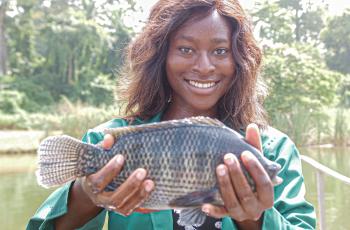 Nigerian youth entrepreneur poses with her farmed tilapia. Photo by Olaniyi Ajibola. 