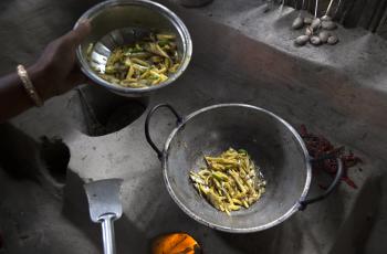 A woman cooking mola and potato curry in her kitchen in Khulna, Bangladesh. Photo by Yousuf Tushar.