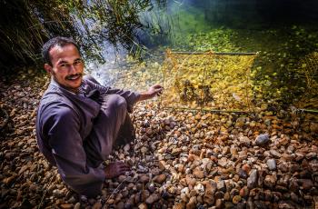 A farmer posing while holding a trap in a fish farm in El-Shahama, Wadi El-Sa’ayda, Edfu, Egypt. Photo by Sara Fouad.