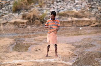 Net mending by a tribal fisher in Odisha. Photo by Sourabh Dubey.