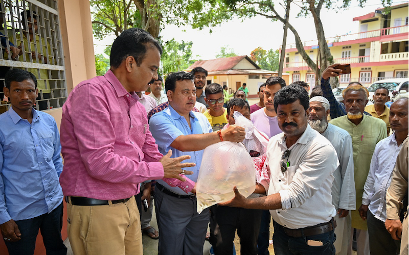 Munindra Nath Ngatey handing over oxygen-packed bags of mola seeds to farmers. Photo: Sourabh Kumar Dubey