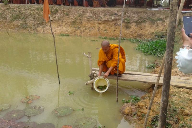 Monk stocking fish, Trapping Kuy, Cambodia.