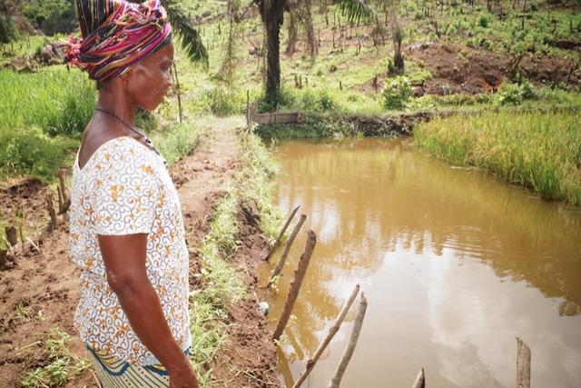 A woman beside a fish pond in Sierra Leone. Photo by Success Kamara